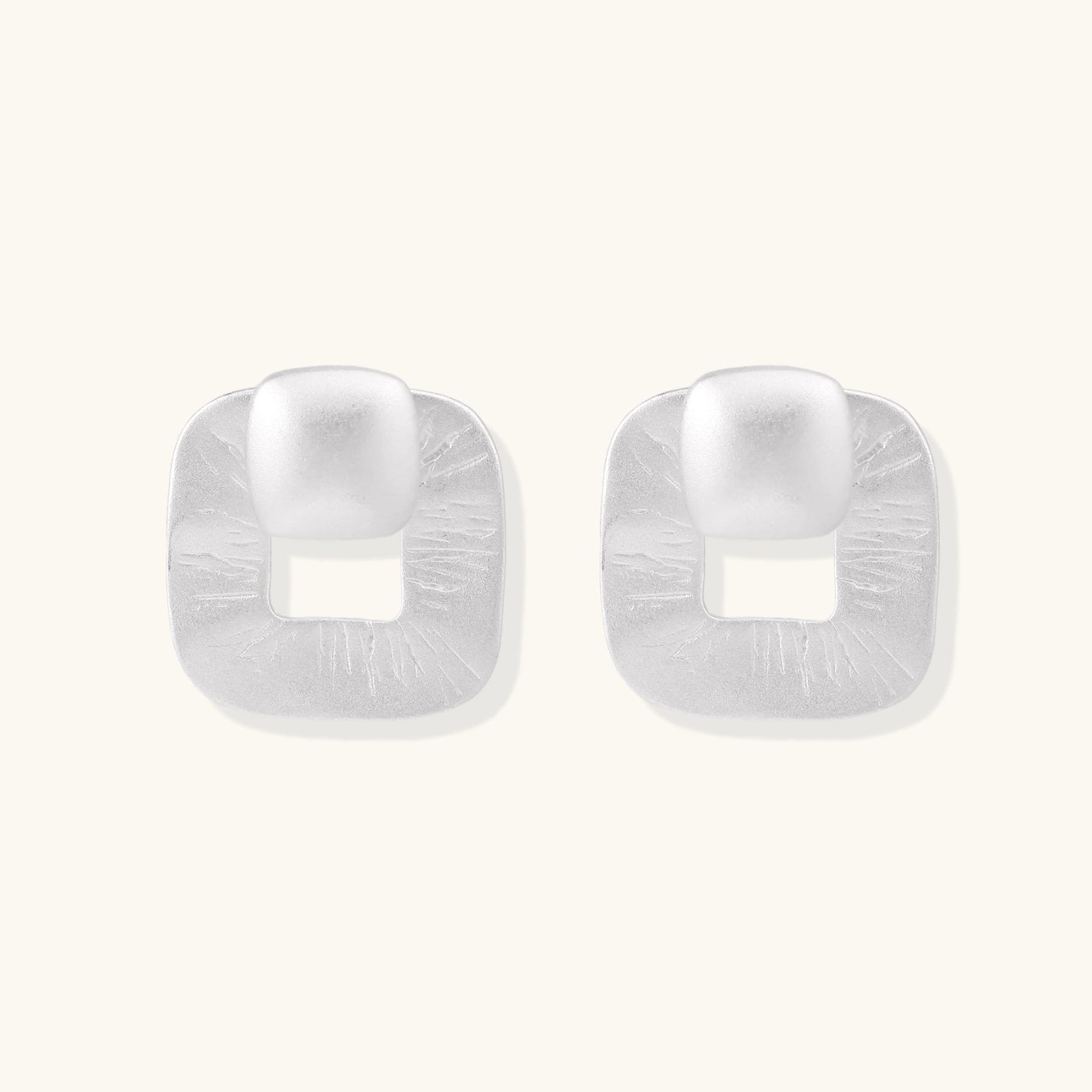 Pair of geometric sterling silver earrings with frosted square frames and glossy rounded studs on white background