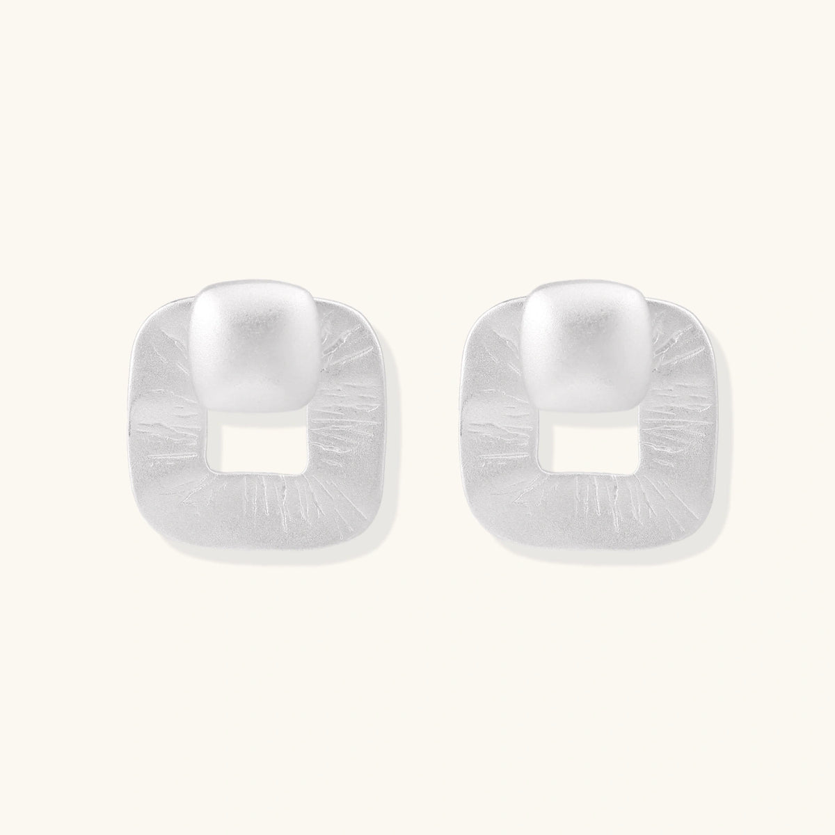 Pair of geometric sterling silver earrings with frosted square frames and glossy rounded studs on white background